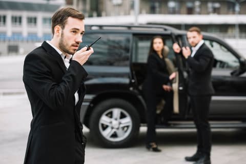 Security team coordinating by radio beside a vehicle