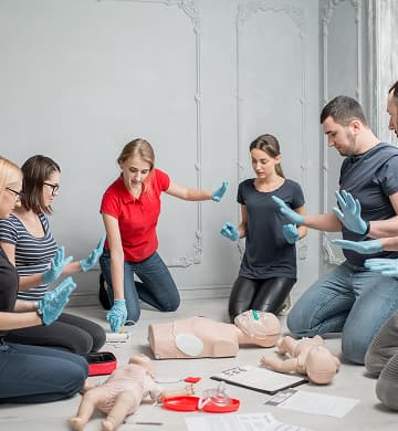 Trainees in gloves practicing bleeding control and CPR on the floor
