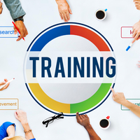 Hands of diverse team members pointing to a colorful training graphic symbolizing research, achievement, and collaboration.