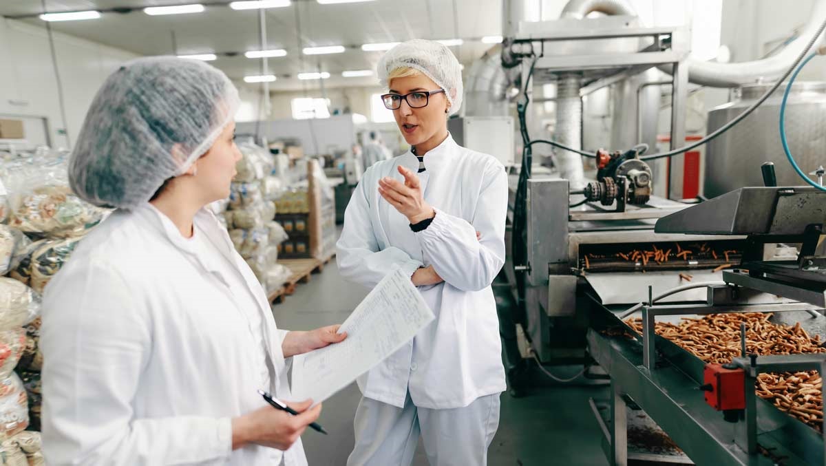 Food production employees conducting safety inspection and training in processing facility