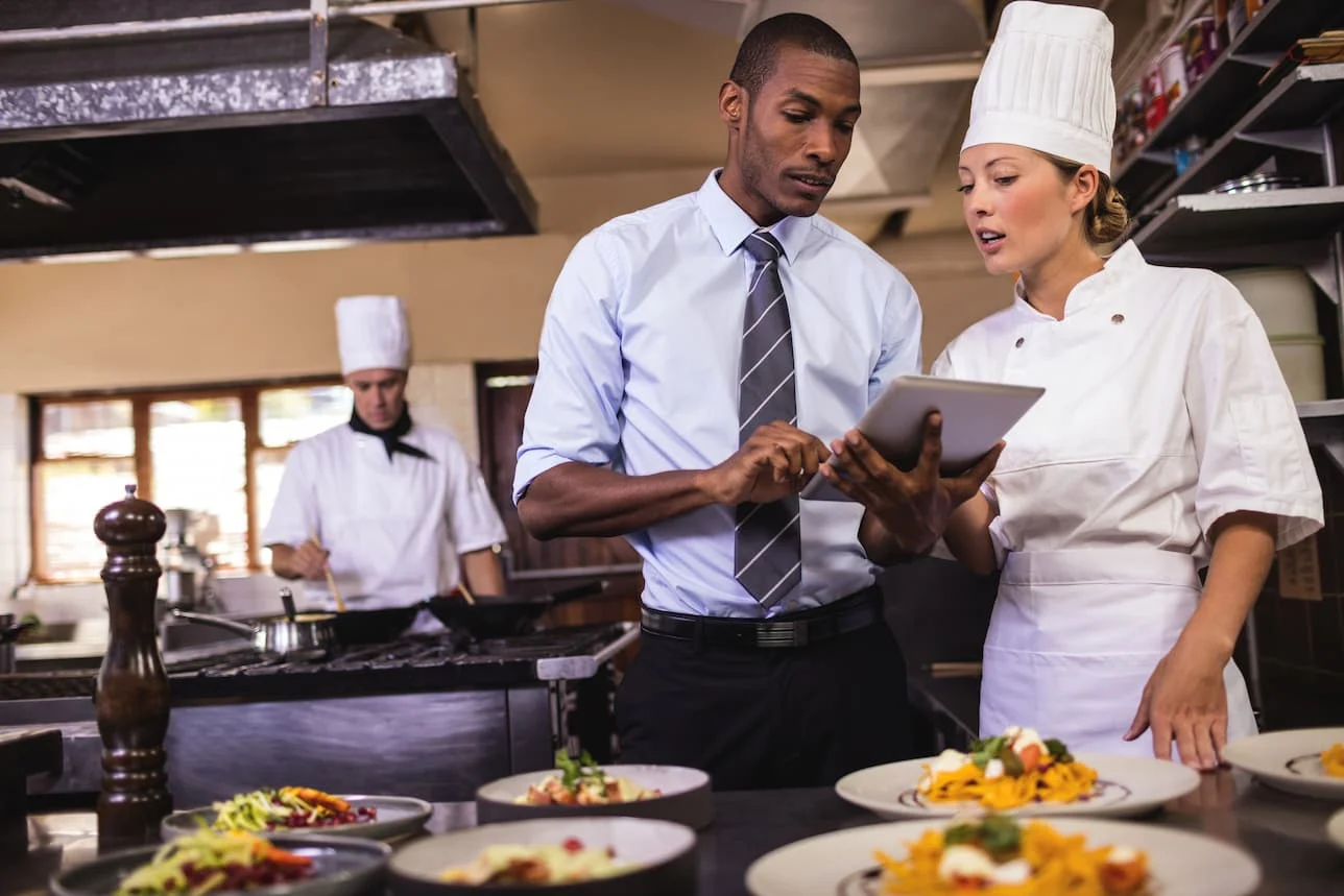 Chef and safety manager reviewing emergency protocols in a commercial kitchen