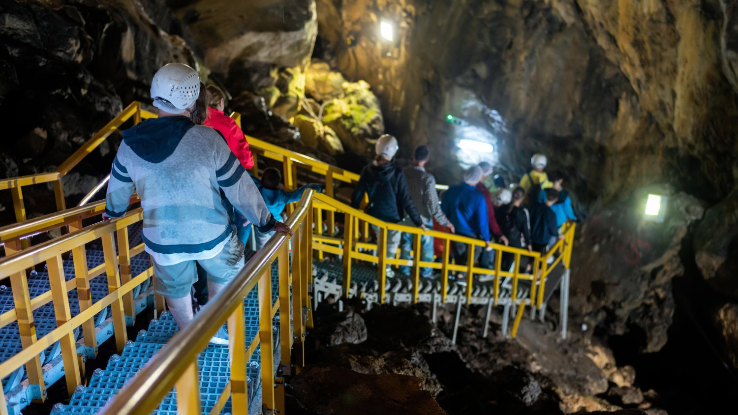 Group of workers with helmets attending mining safety training inside cave.”
