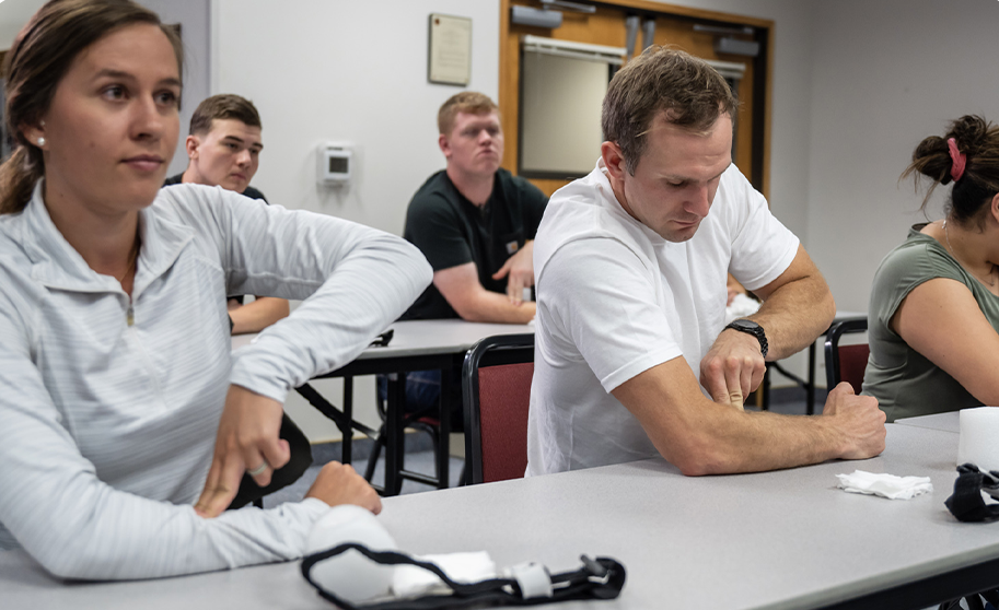 Participants in AVIRT School Safety Training practicing stop-the-bleeding techniques in a classroom setting, emphasizing hands-on emergency response skills.